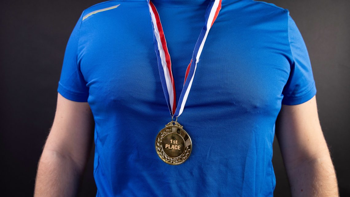 A blue shirt and chest is shown with a first place medal around his neck. Image: Jernej Furman, CC