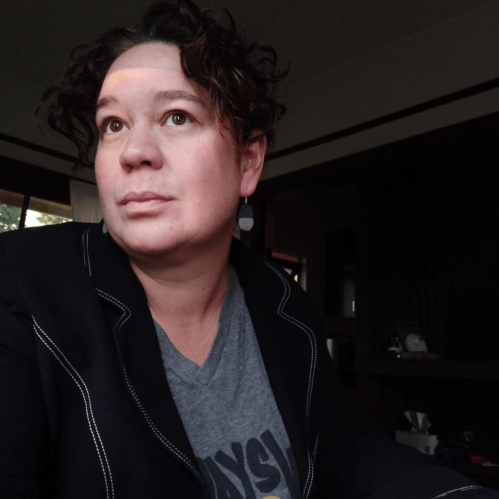 Lyndal Cairns is seen in a black jacket and grey shirt, looking out of the frame.